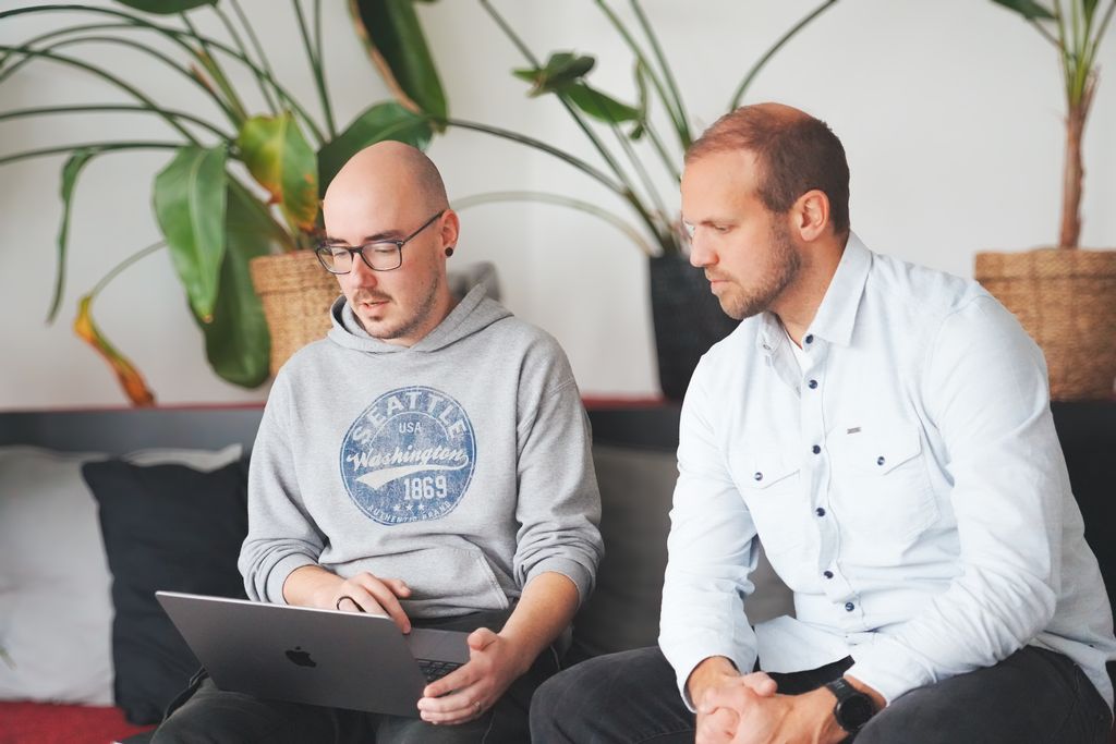 Zwei Kollegen arbeiten gemeinsam an einem Laptop im Büro